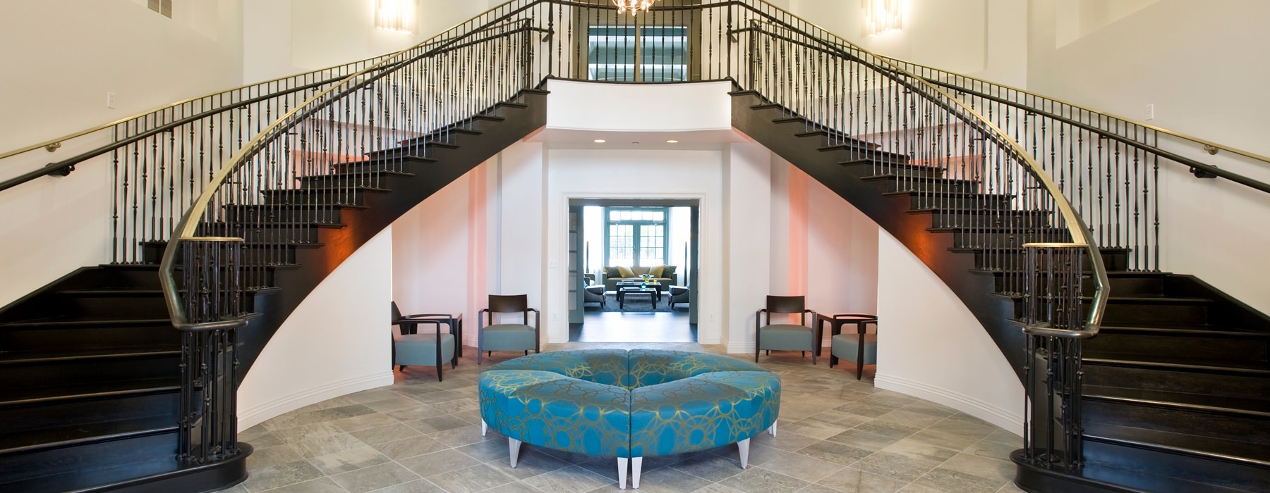 Large lobby with dual curving staircase and circular couch seating.